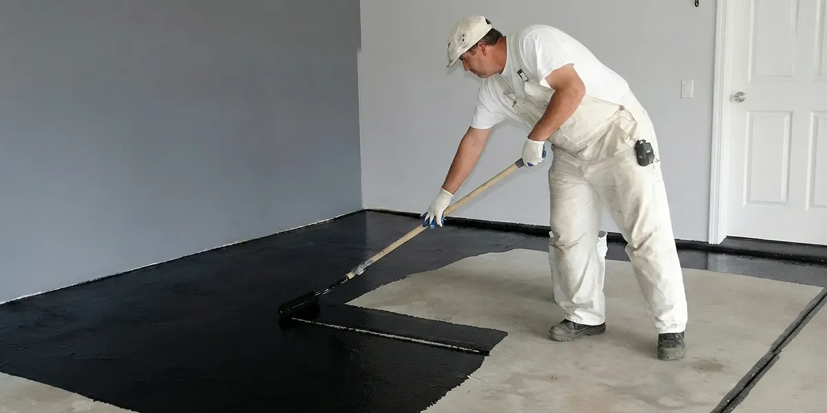 basement waterproofing professional applying waterproof coating to protect a basement floor in Chicago, IL